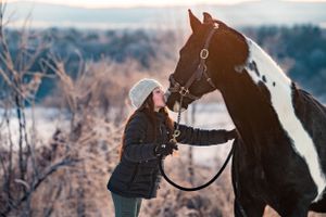 girl kissing black and white horse