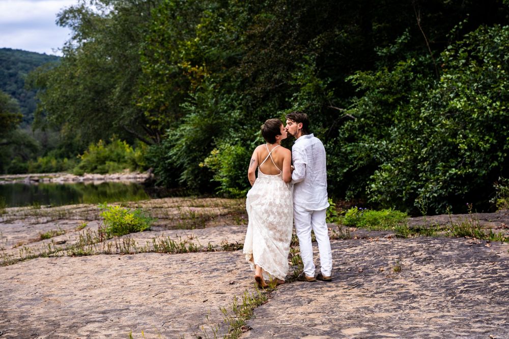 A newlywed couple kiss in a scenic outdoor location