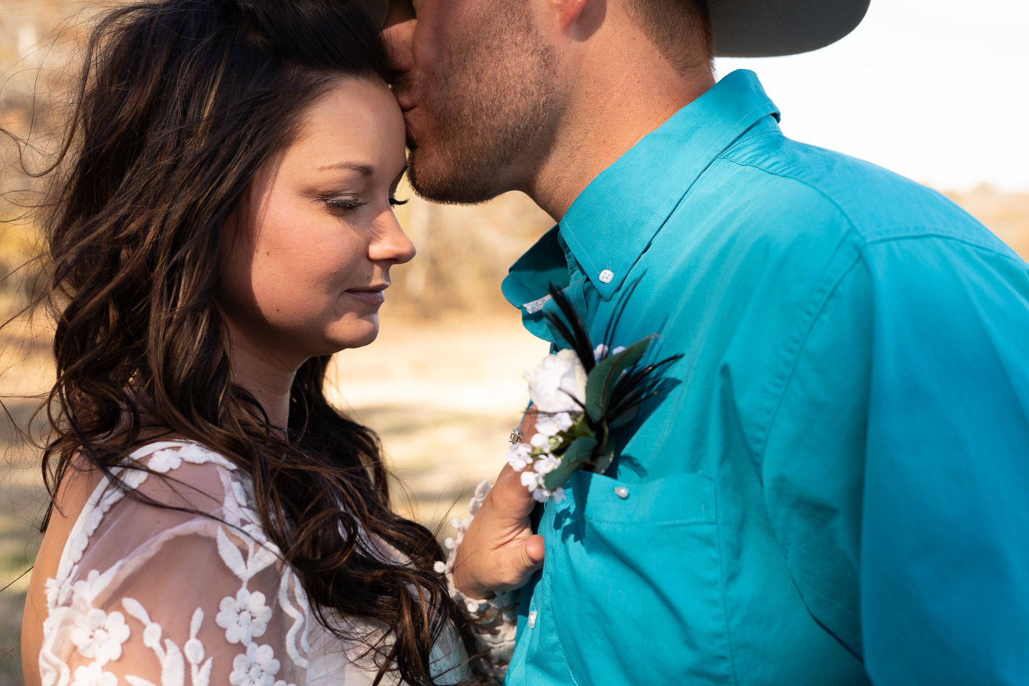 A groom kisses bride on the forehead