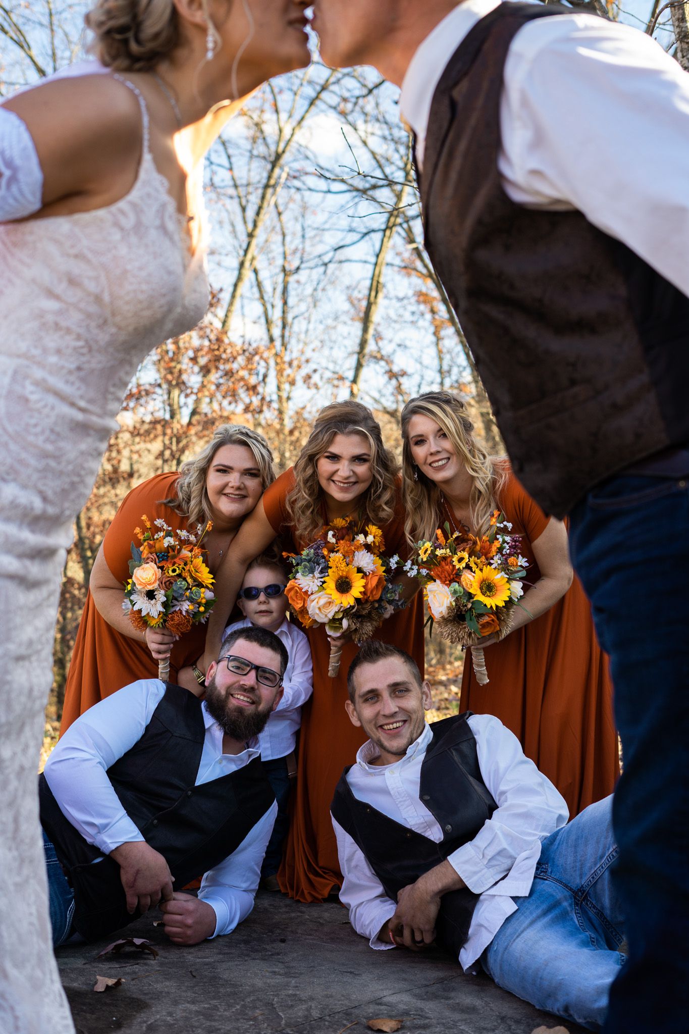 A bride and groom kiss in front of bridal party