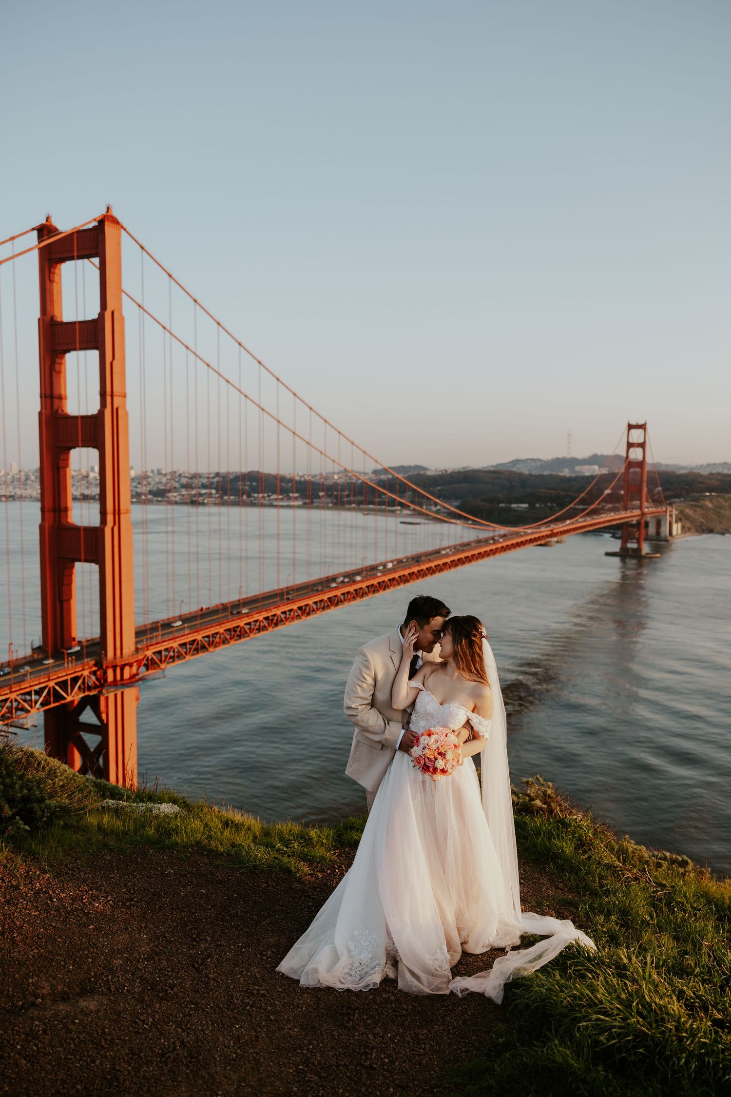bride and groom holding each other with the Golden Gate Bridge in the background on their san francisco elopement day