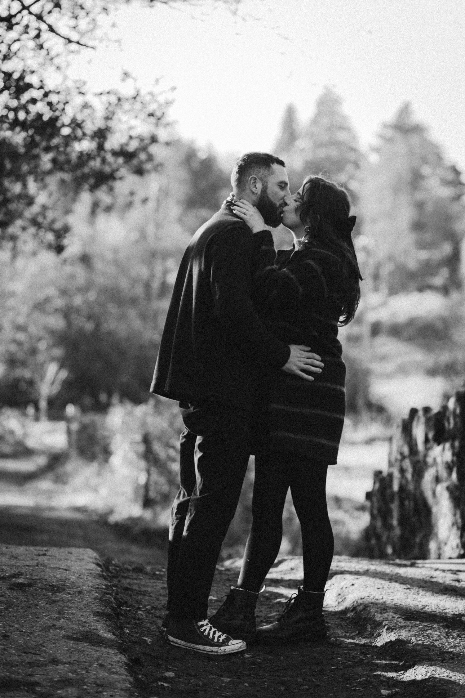 Black and white portrait of couple sharing romantic moment on woodland path.
