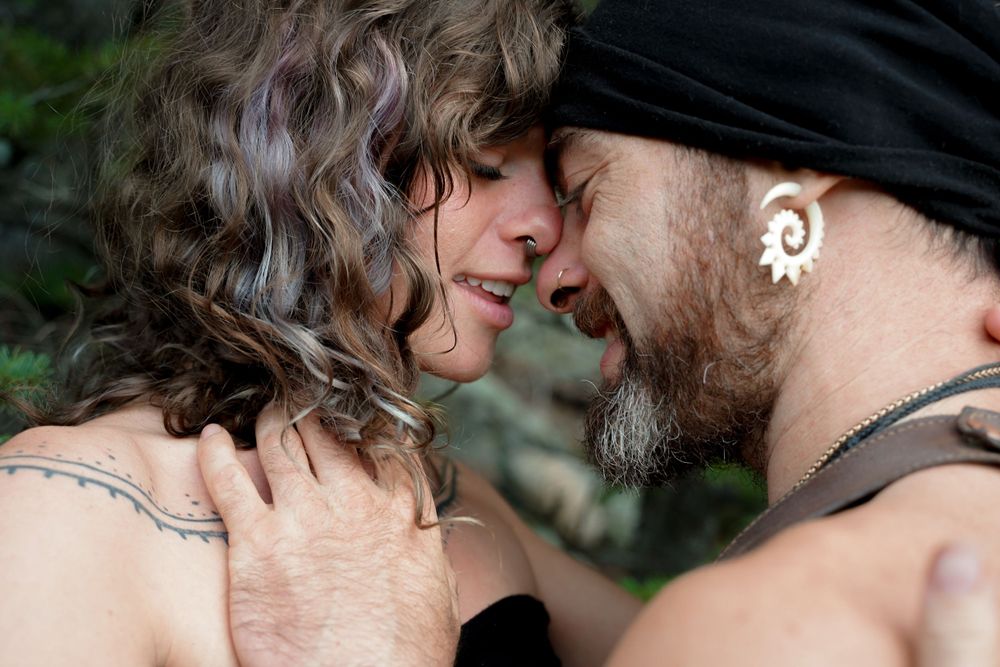 Intimate outdoor portrait of a couple sharing a tender moment against a natural background.
