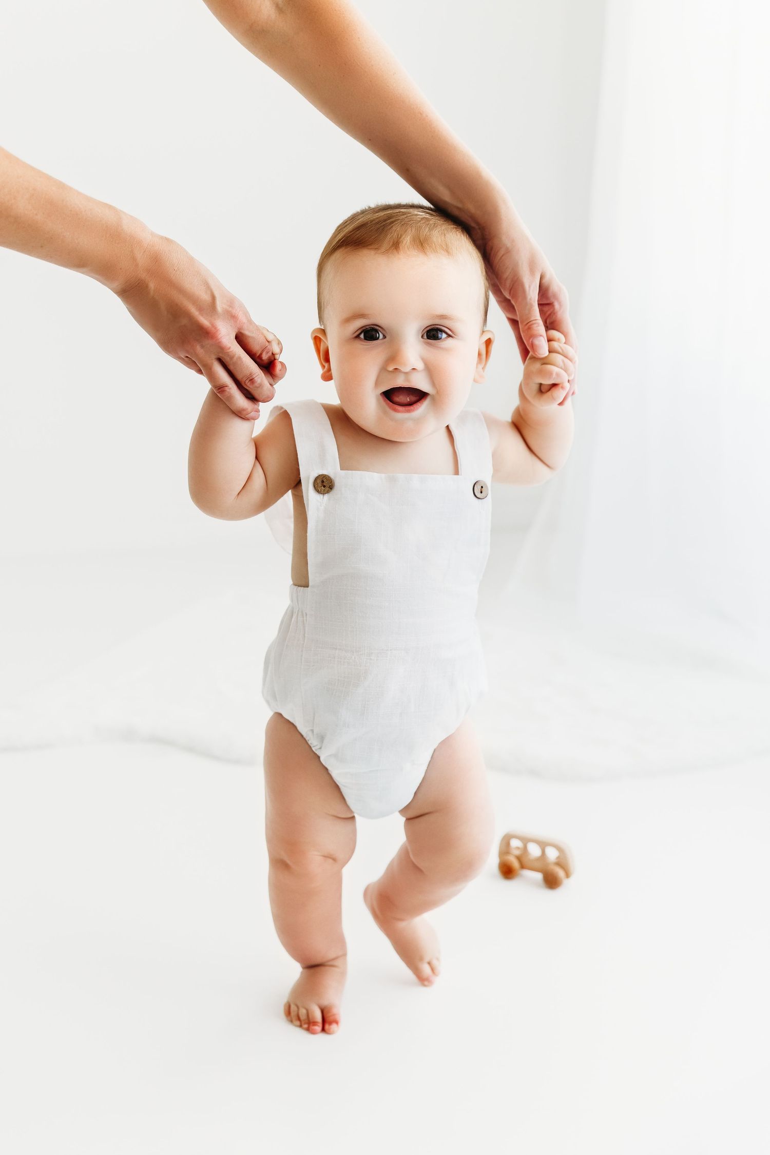 Baby Boy holding onto Mom's hands, learning to walk