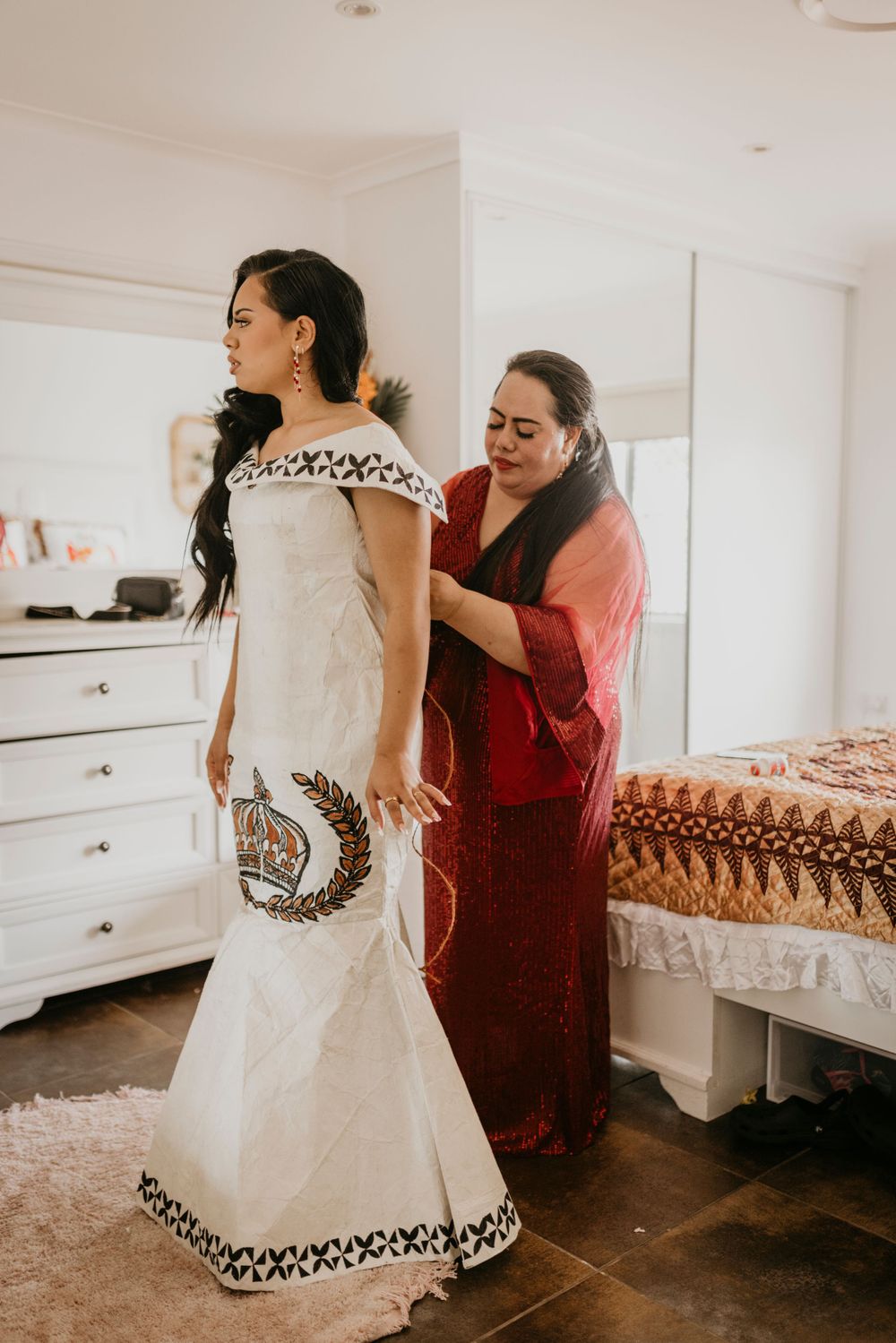 a mother prepares her daughter for her formal and helps put her dress on