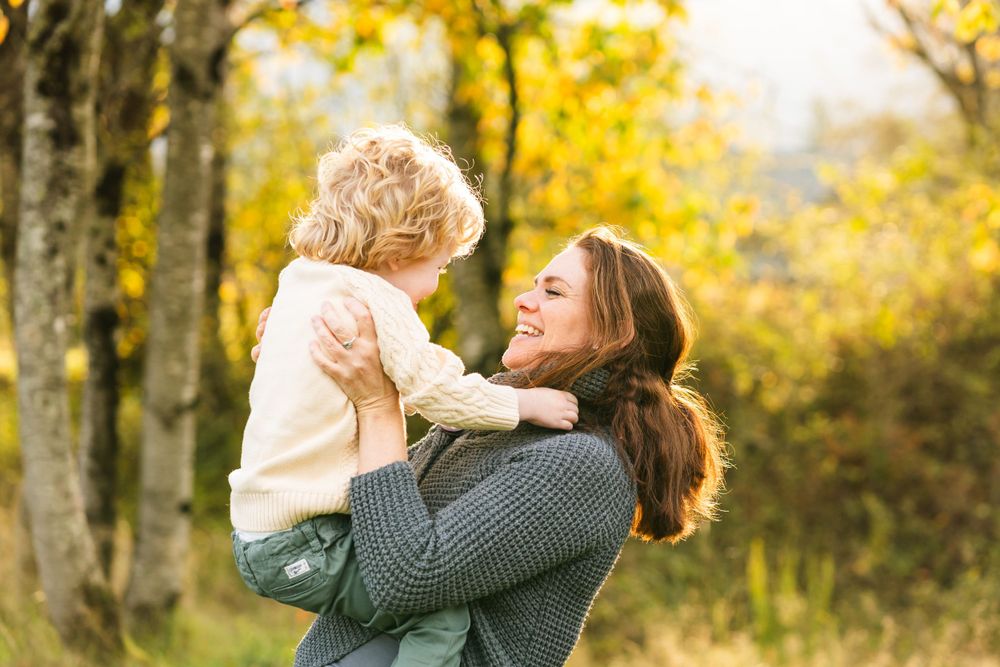 Mother smiling while holding her son up at sunset in North Bend.