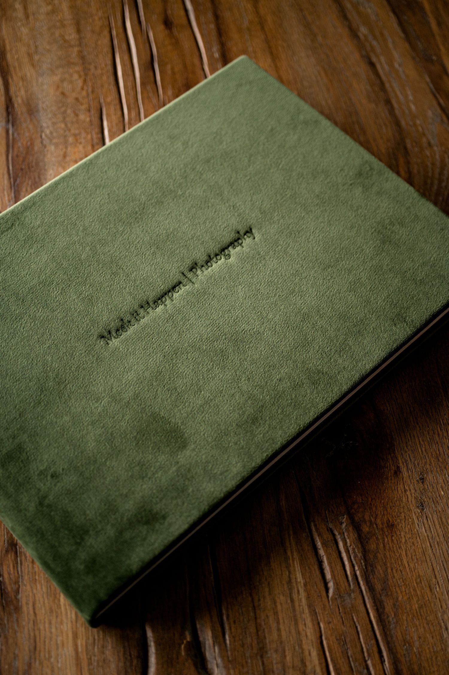 Elegant green suede photo album displayed on wooden surface.