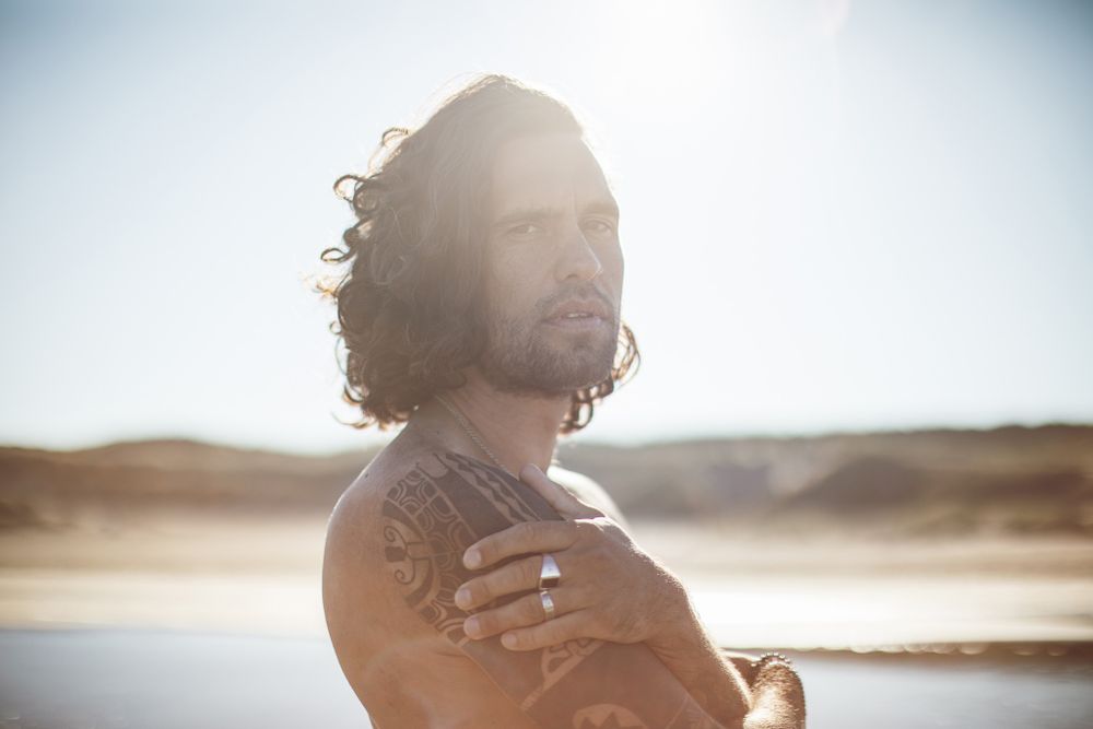 Person in white clothing stands against a bright backlit sky during golden hour.