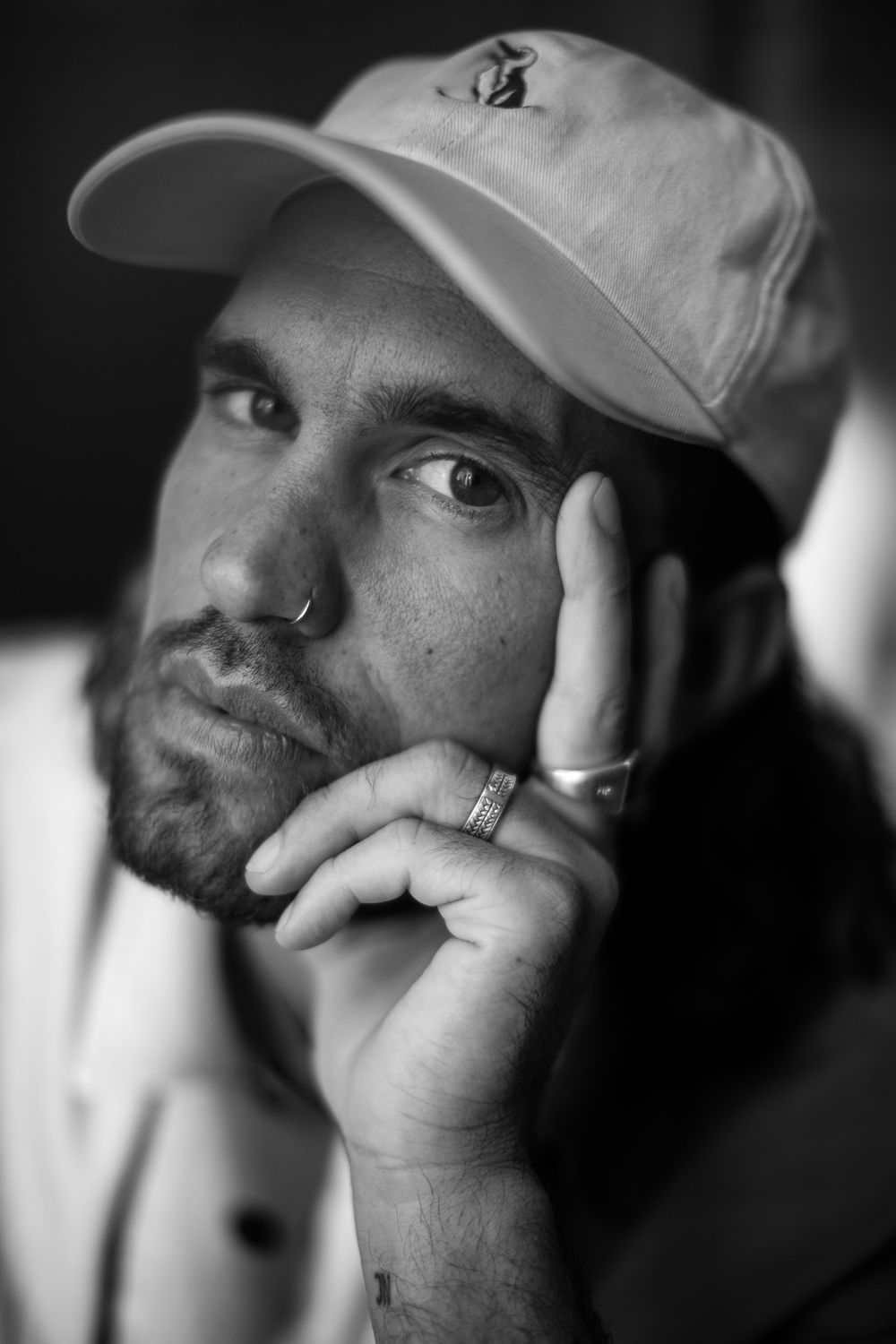A close-up black and white portrait of someone wearing a baseball cap.