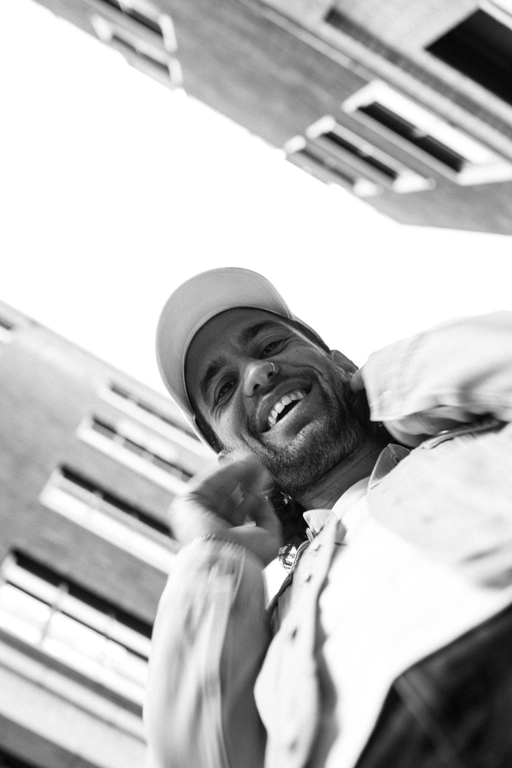 Black and white candid portrait of someone in a baseball cap smiling.