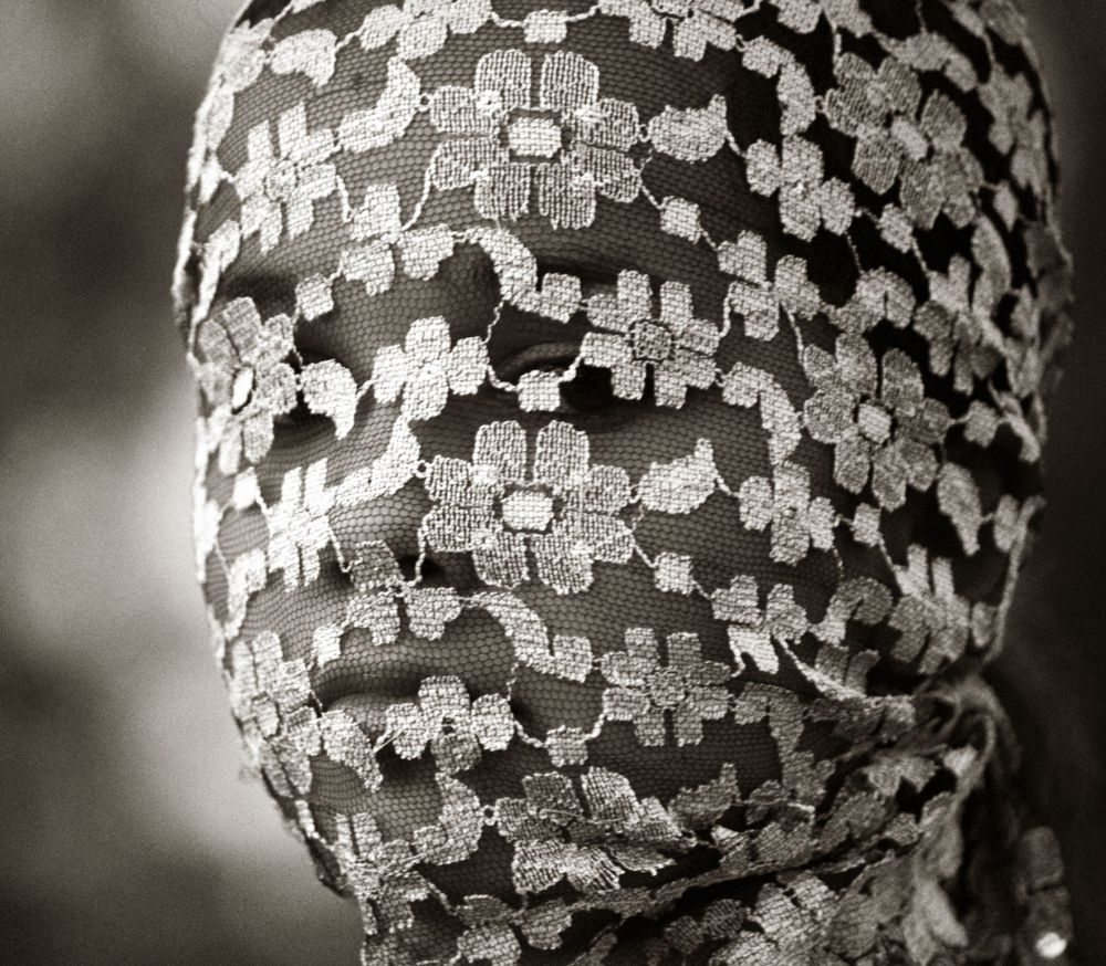 Close-up black and white photo of delicate lace fabric with floral pattern.