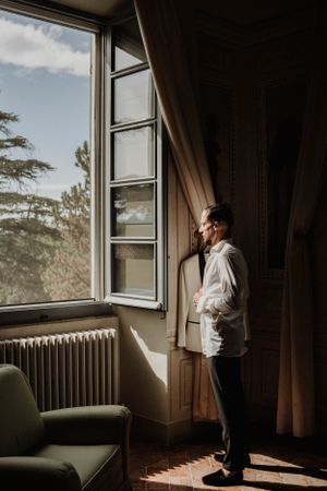 A person gazes out of a tall window in an elegant room with vintage radiator.