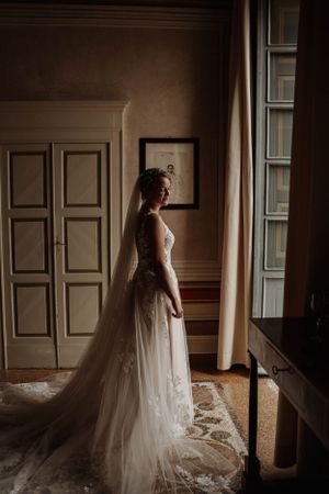 A wedding dress silhouette illuminated by natural window light in an elegant room.