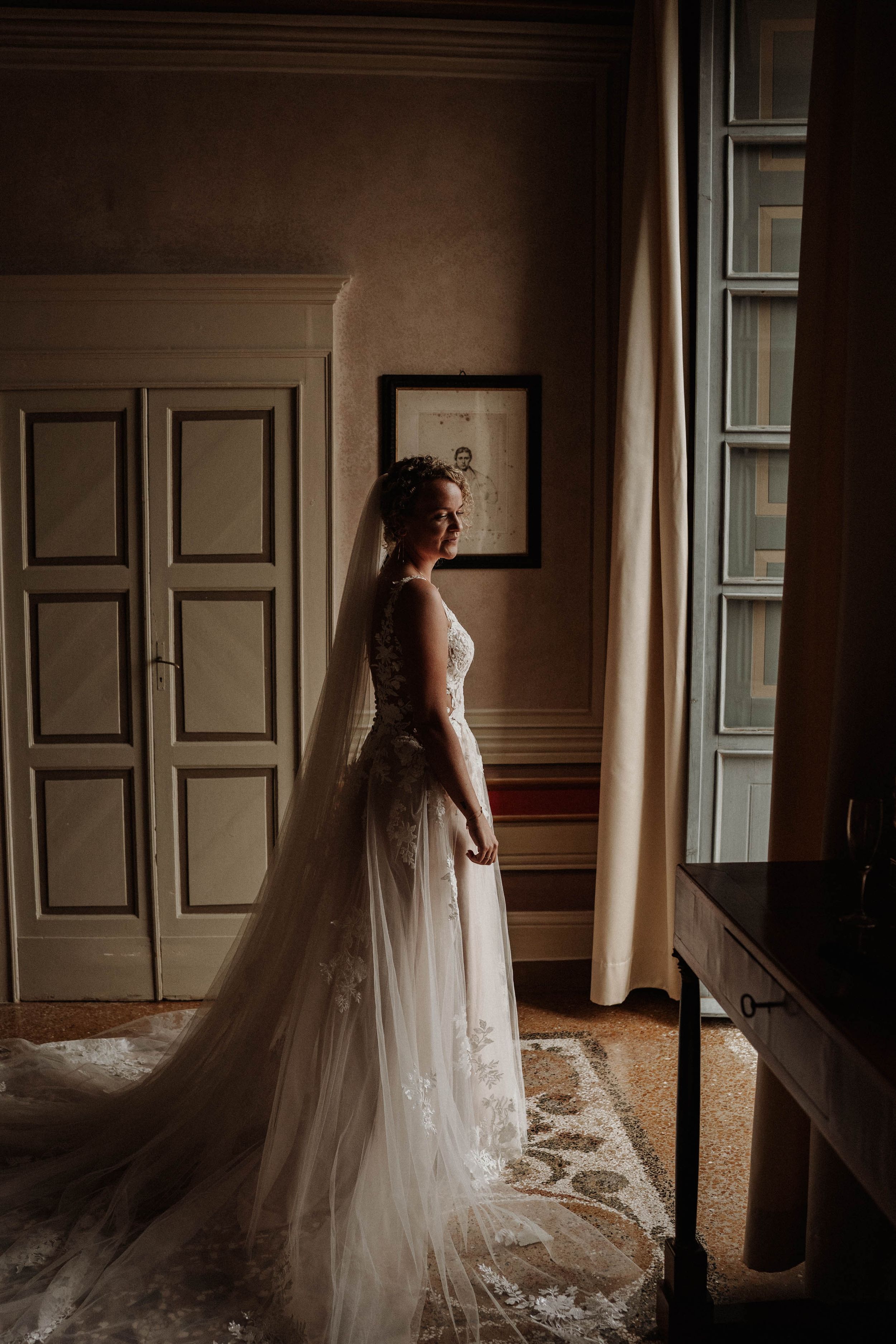 A wedding dress silhouette illuminated by natural window light in an elegant room.