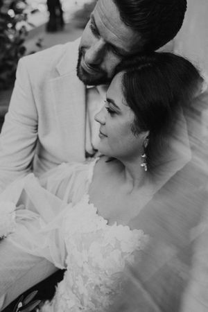 Black and white intimate portrait of newlyweds in elegant attire.