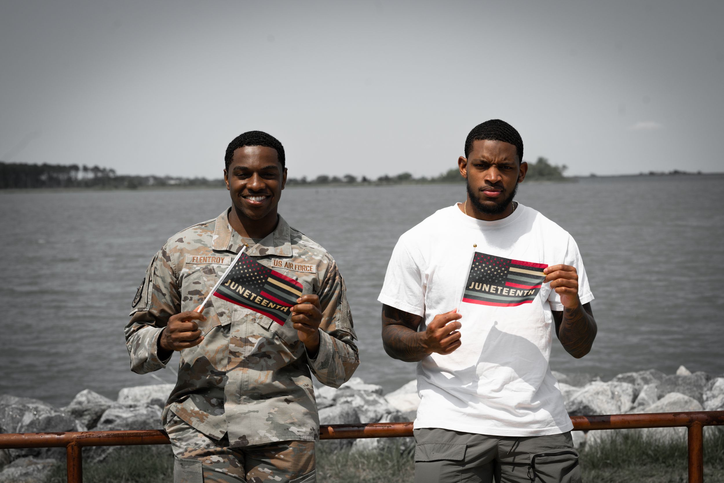 People holding papers while posing together near waterfront railing.