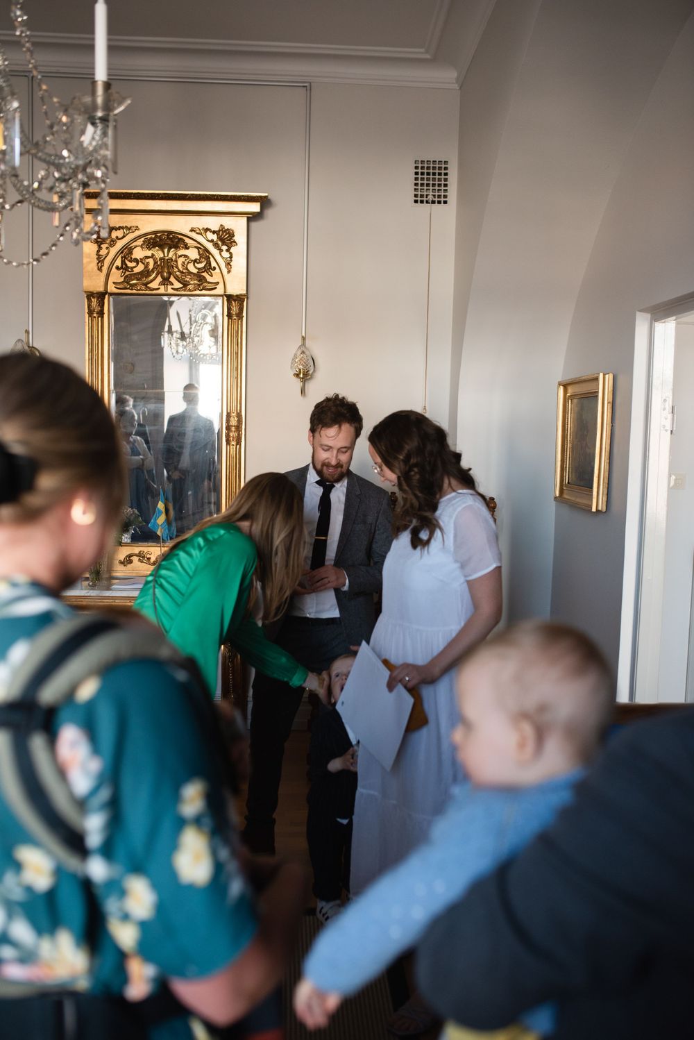 Intimate gathering in a bright room with decorative mirror and chandelier.