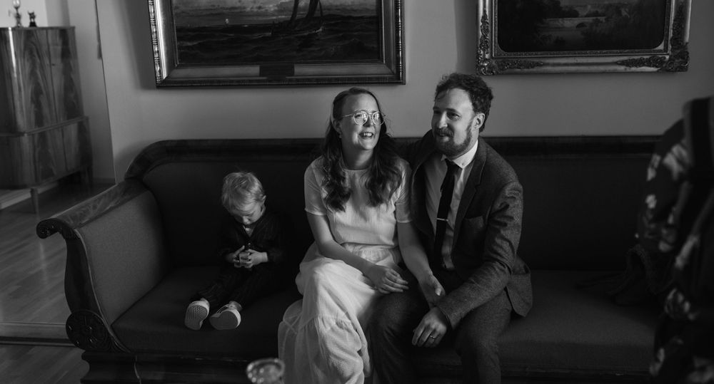 Family moment captured on blue sofa with vintage artwork in background.