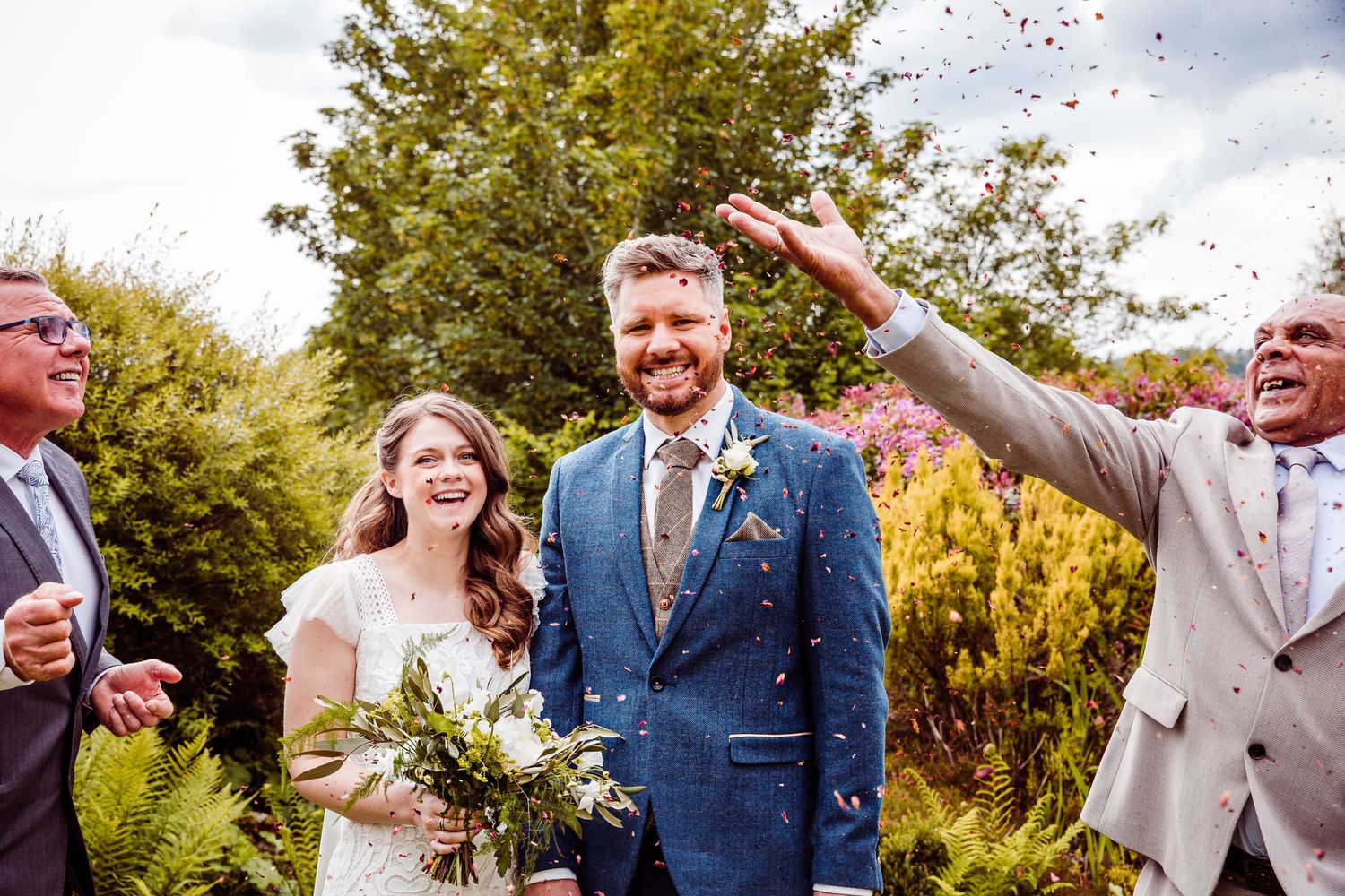 Wedding celebration moment with confetti being thrown in a sunny garden setting.