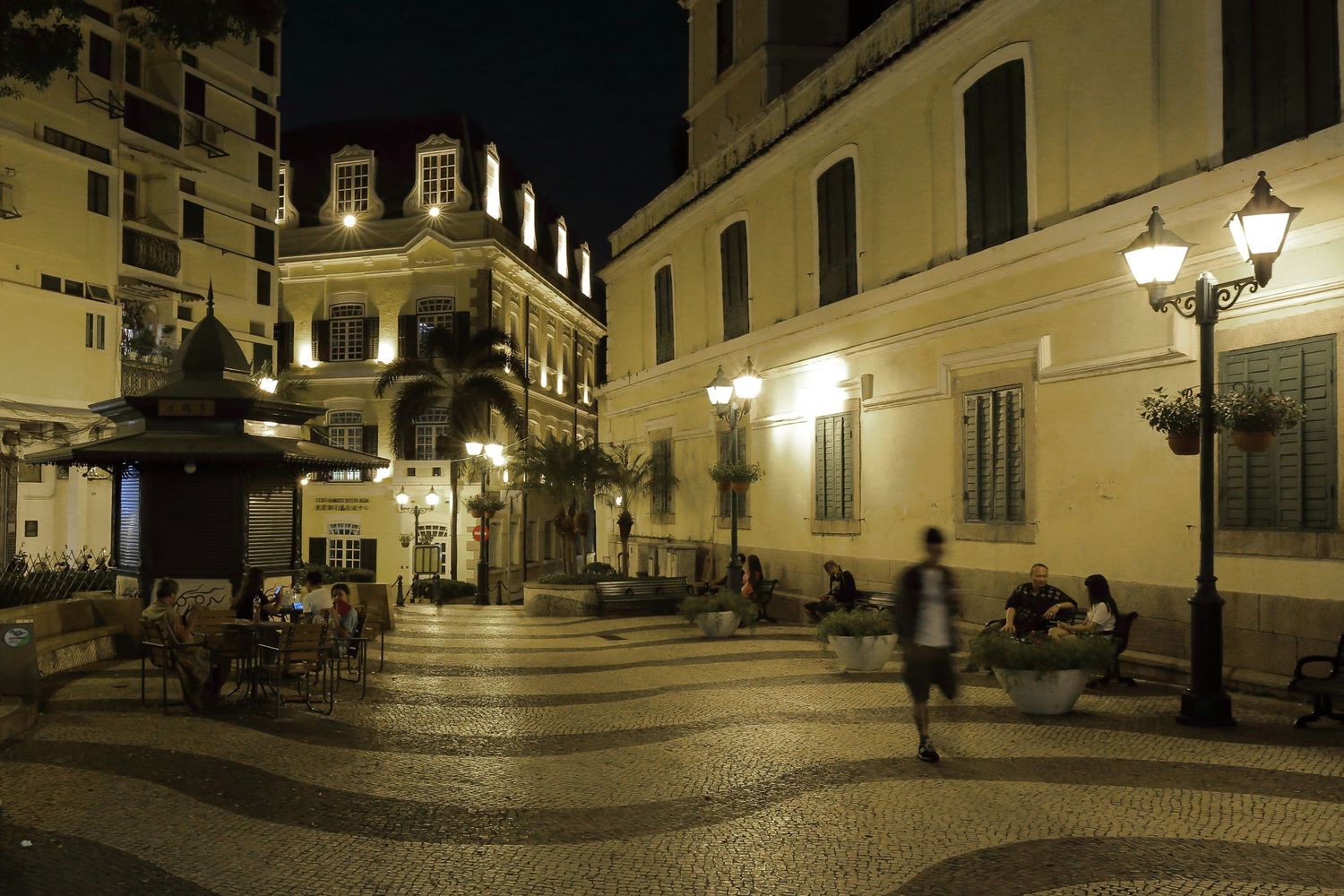 Historic colonial square in Macau at night with street lamps and architecture.