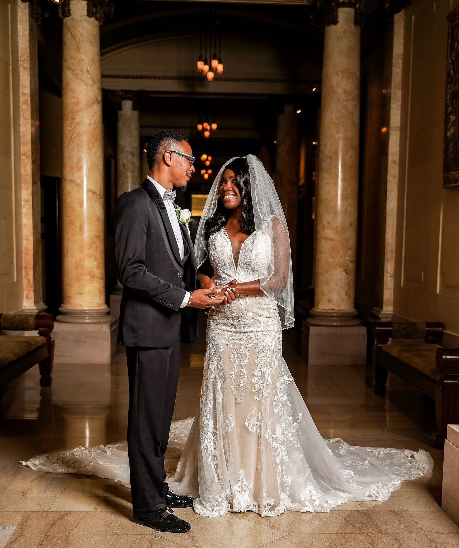 Romantic first dance between newlyweds in a grand hall with marble columns.