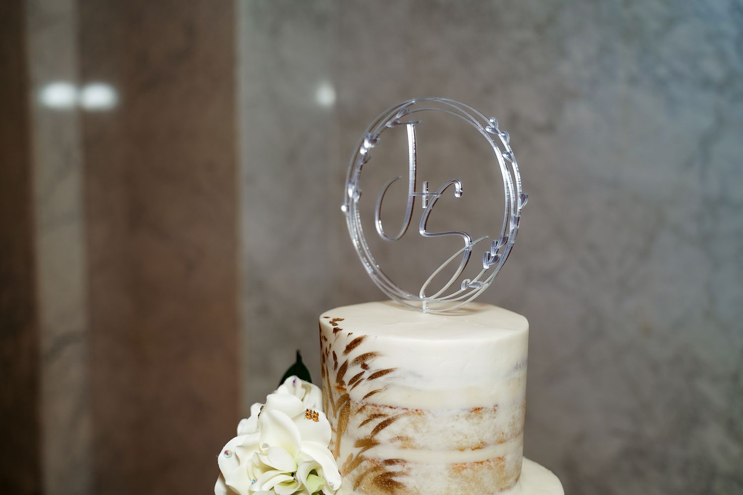 White wedding cake decorated with delicate floral details and metallic accents.