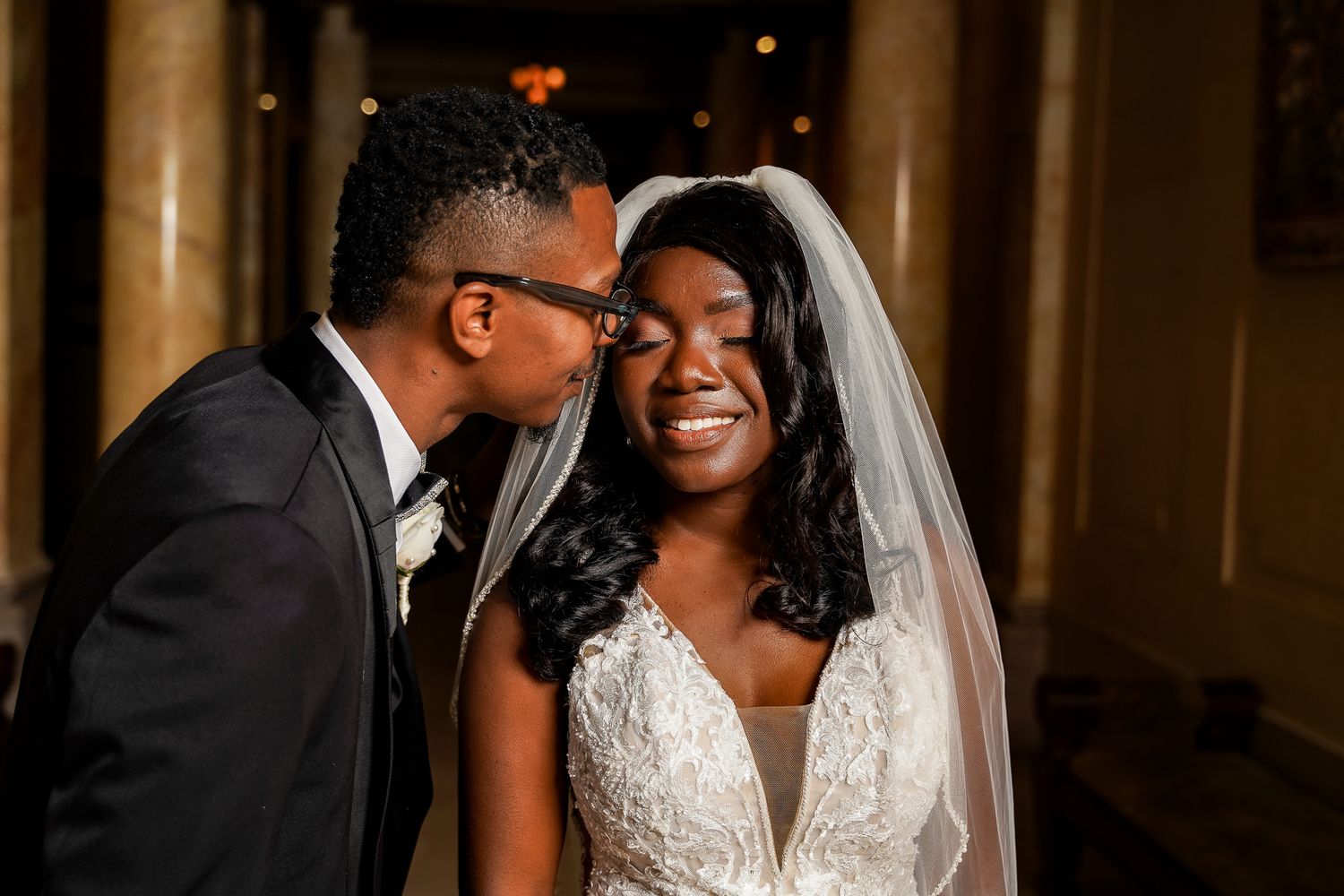 Intimate wedding moment captured in elegant venue with classical architecture.