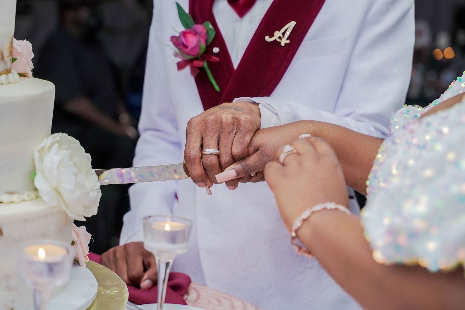 Wedding ceremony detail shot showing hands with rings and white floral decorations.