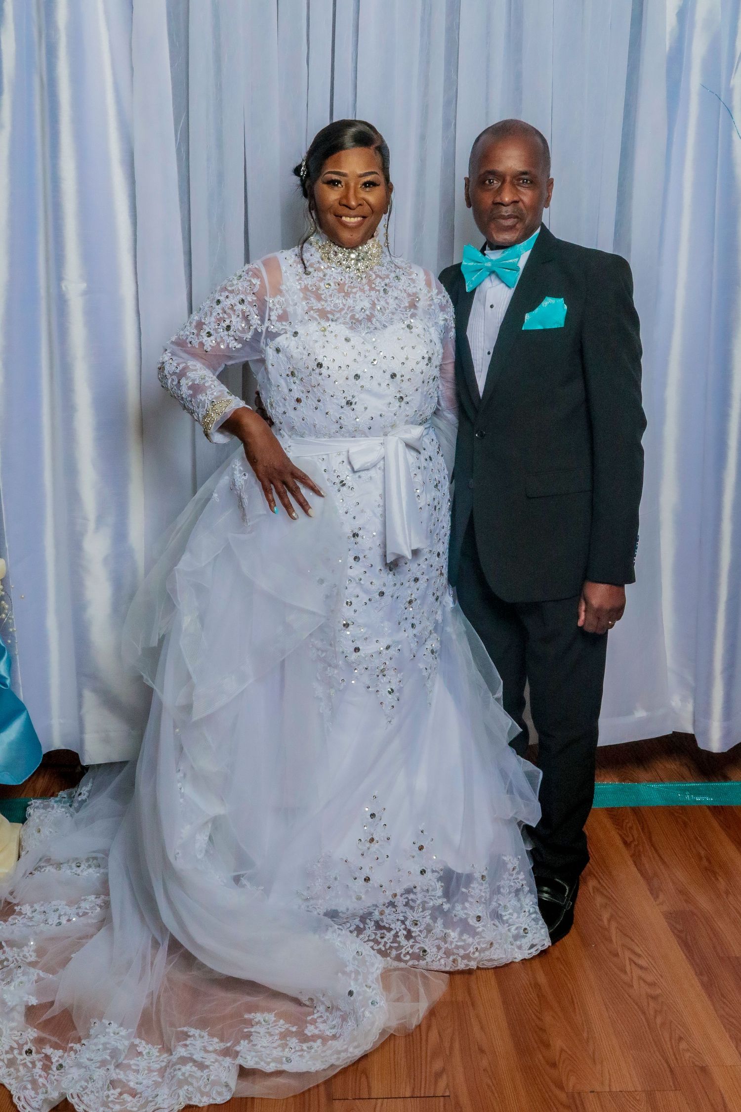 Wedding portraits against white curtain backdrop featuring elegant white lace gown.