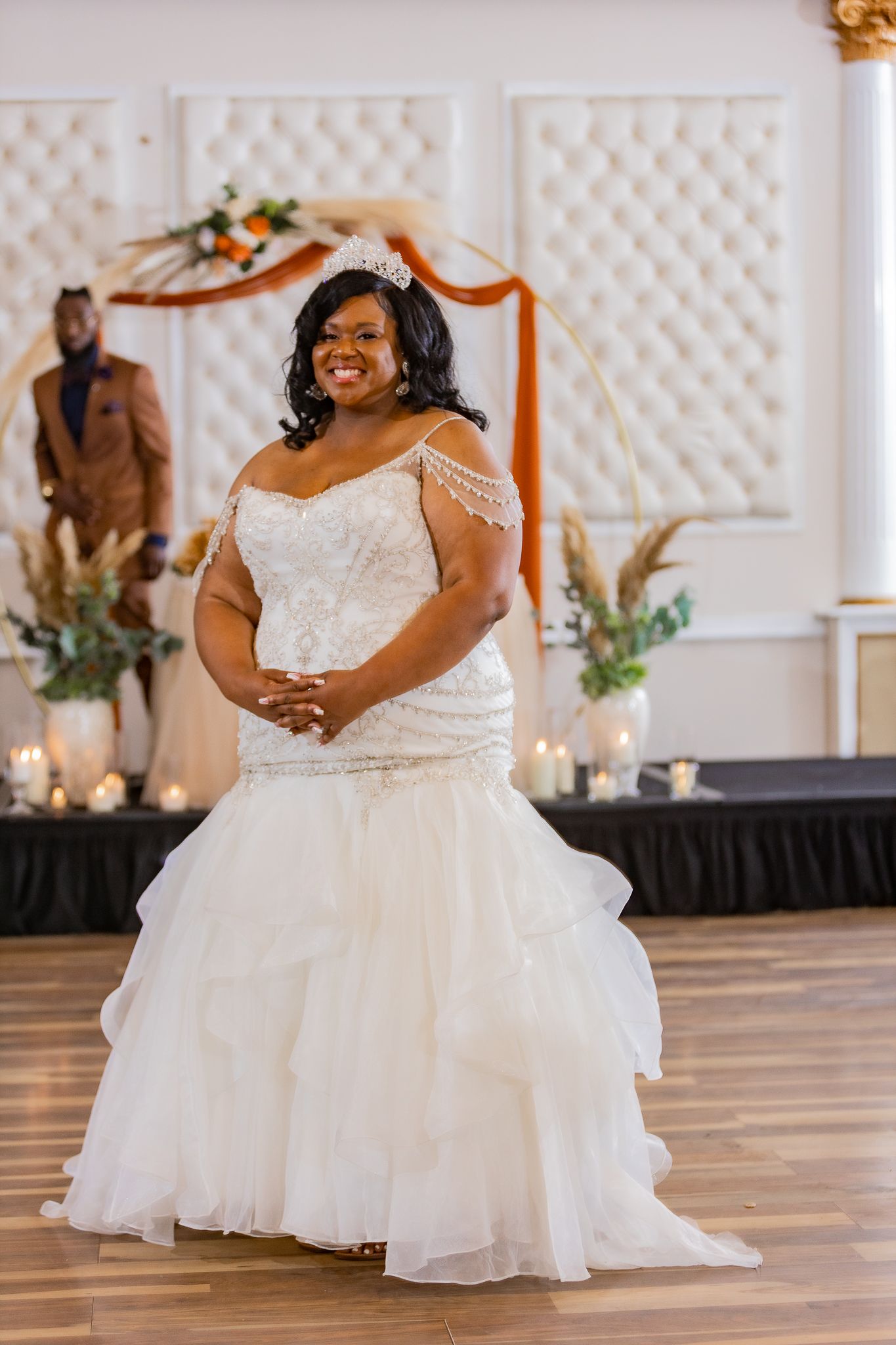 Bride in an elegant white ball gown twirling on a wooden dance floor with lattice backdrop.