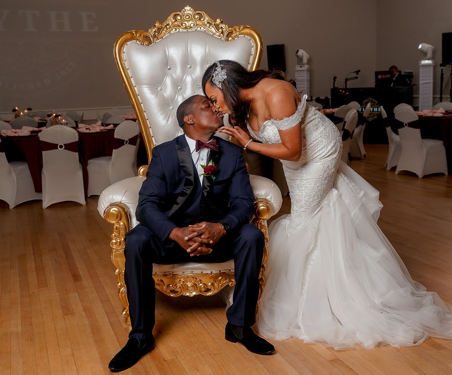 Ornate gold throne chair setup for wedding ceremony in elegant ballroom.