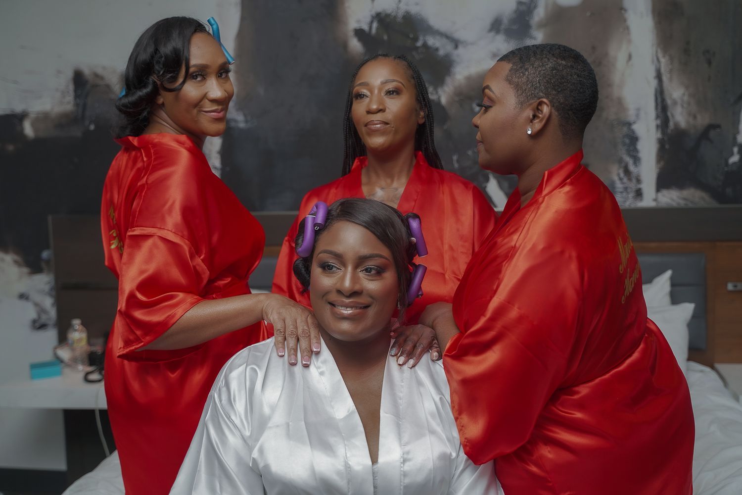 Wedding party members in red silk robes and white attire share joyful moments during pre-ceremony preparations.