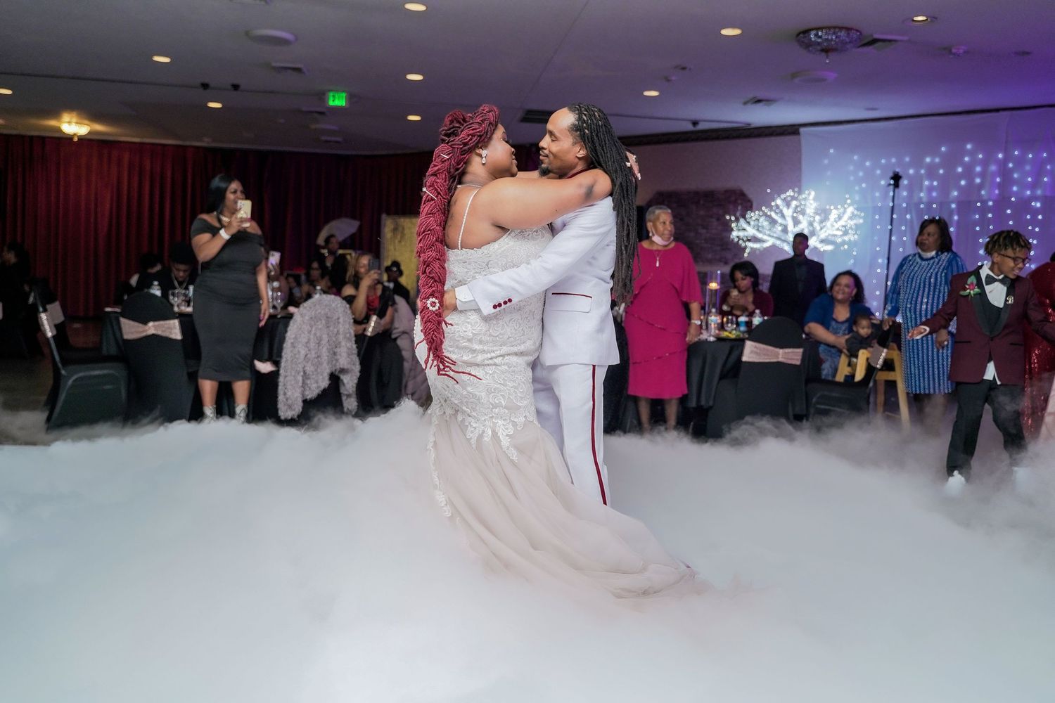 A couple shares their first dance on a misty dance floor at their wedding reception.