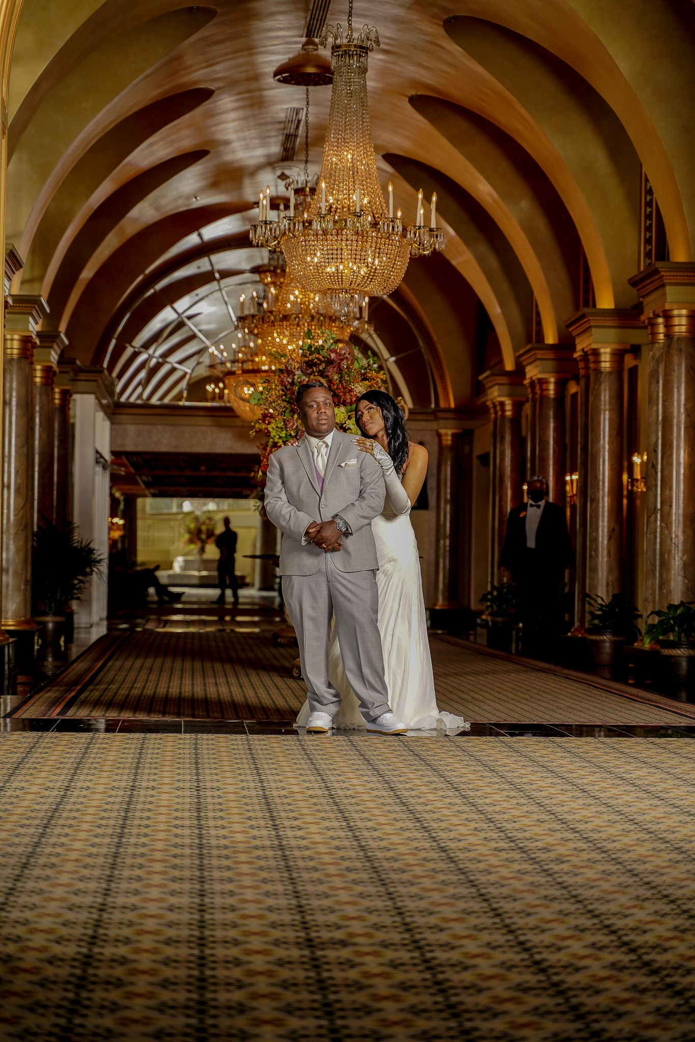 Grand hallway with arched ceilings and crystal chandeliers creates dramatic wedding venue atmosphere.