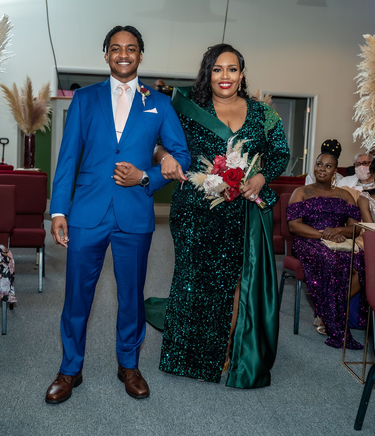 Wedding party members in formal attire featuring a royal blue suit and emerald sequined gown.