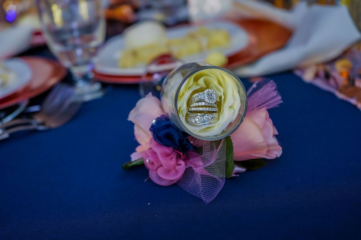 Wedding reception table details with pink roses and decorative elements on navy blue tablecloth.