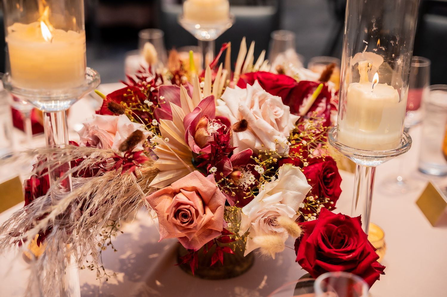 Romantic wedding centerpiece with red and pink roses, candles and gold accents.