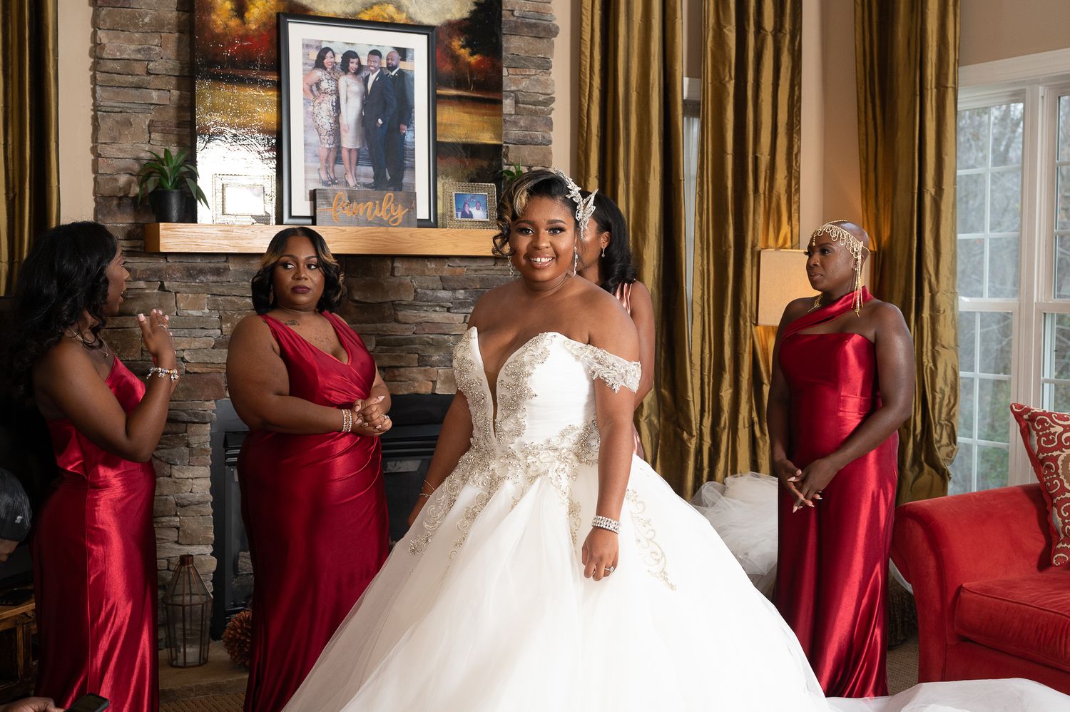 A bride in a white ballgown stands surrounded by bridesmaids in red dresses.