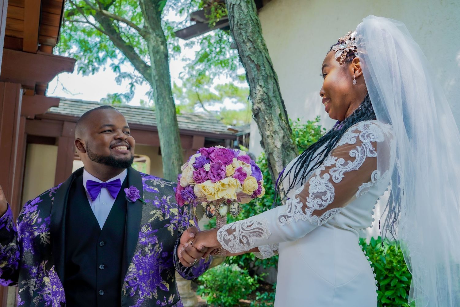 Wedding couple shares joyful moments outdoors with purple floral decorations in the background.