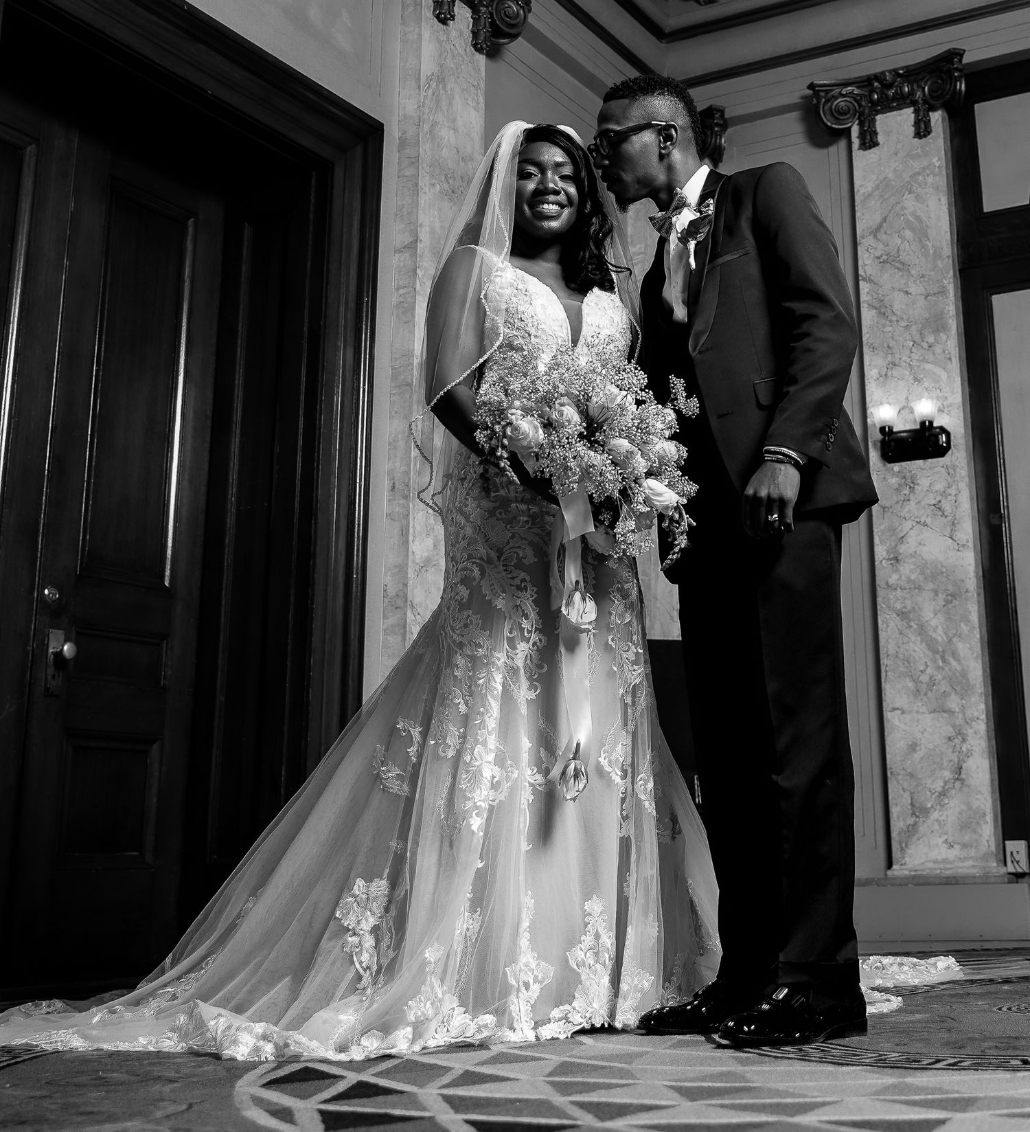 Black and white wedding photos showing tender moments between newlyweds in an elegant hallway.