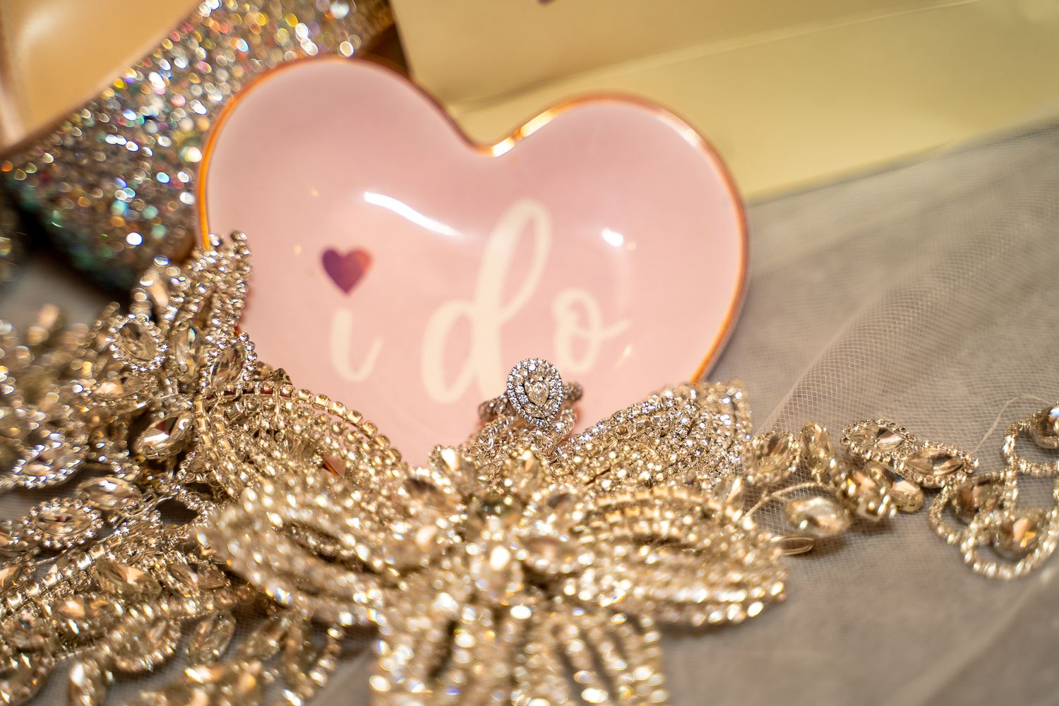 Close up of pink heart-shaped dish with sparkly bridal jewelry and accessories.