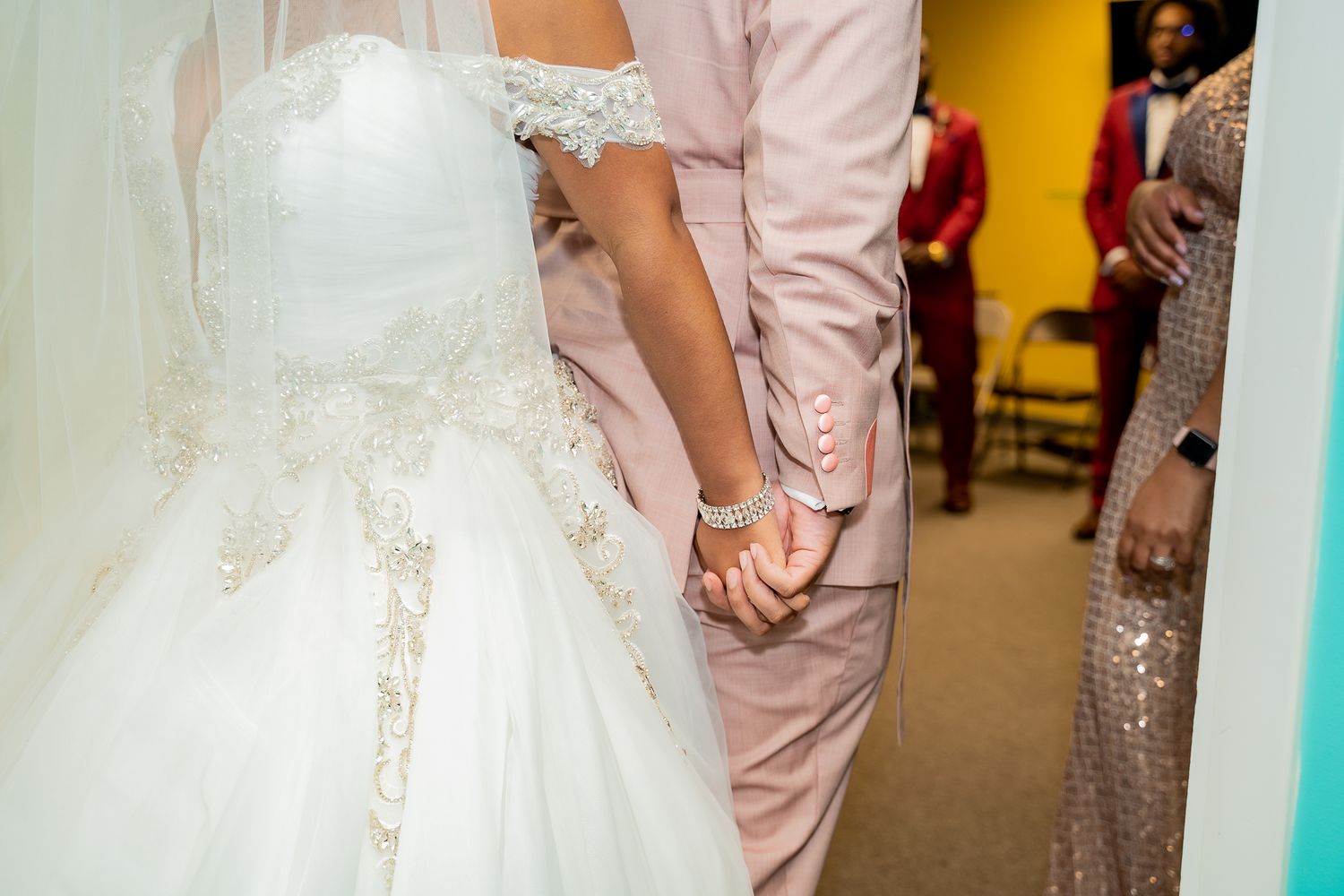 Close up of a bride and groom holding hands during their wedding ceremony.
