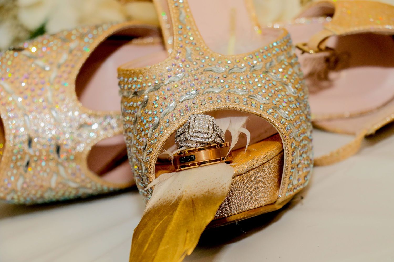 Sparkly gold and crystal wedding shoes displayed among soft pink decor elements.