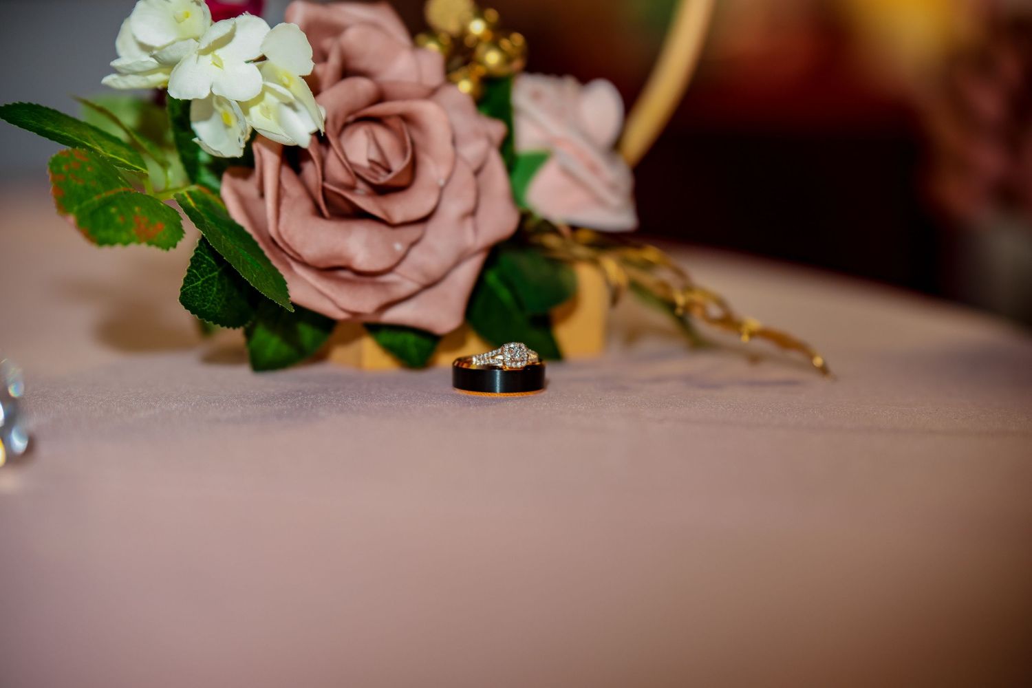 Wedding rings displayed next to pink roses and floral decorations.