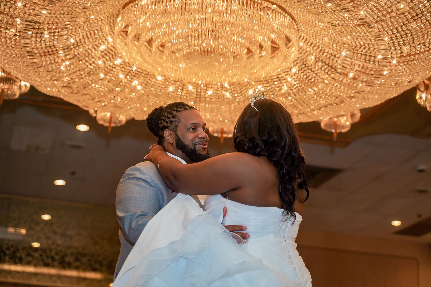 Elegant ballroom wedding reception with crystal chandeliers and romantic lighting.