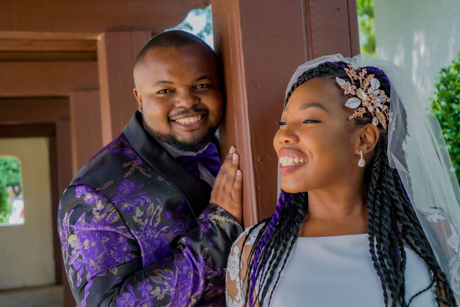 Couple laughing together during outdoor wedding photoshoot with natural greenery backdrop.