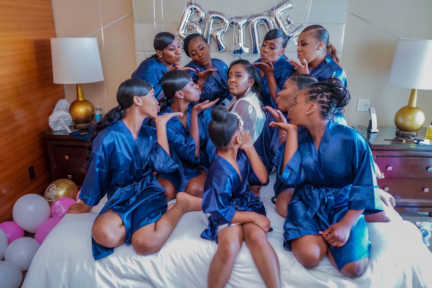 Bridesmaids in blue robes celebrating with the bride during pre-wedding preparations.