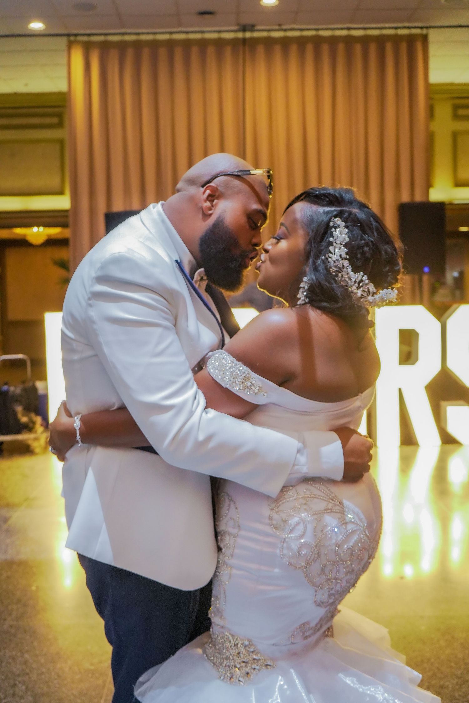 Romantic first dance between newlyweds in an elegantly lit ballroom.