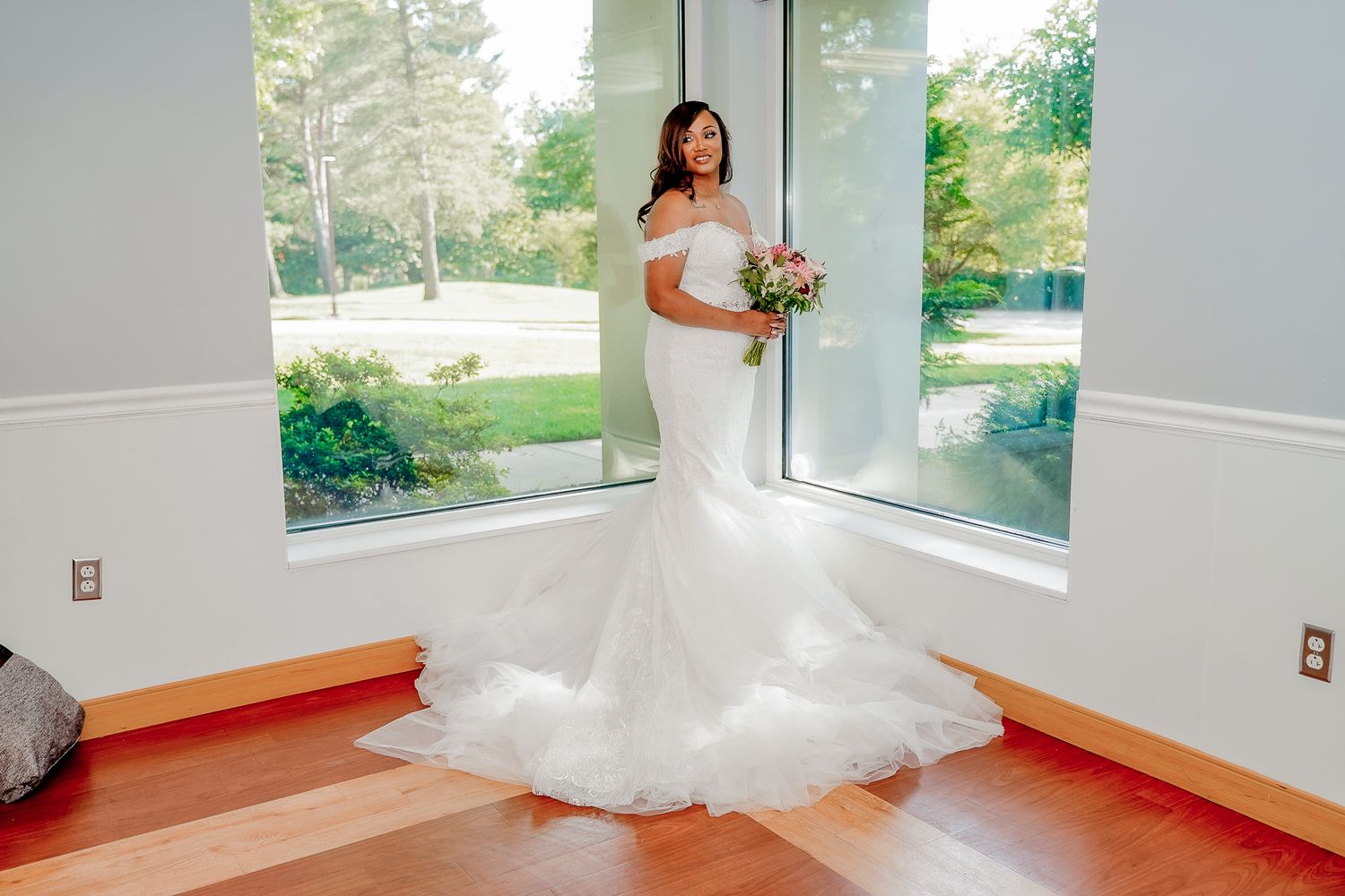 Bright sunlit bridal preparation room with large windows and hardwood floors.