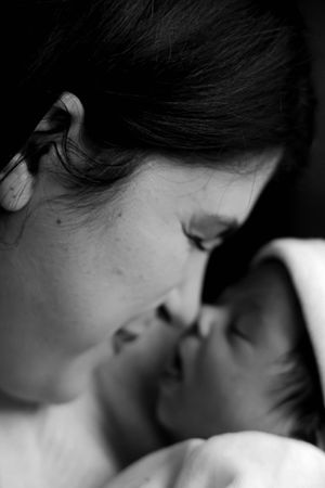 Intimate black and white close-up photograph showing tender moment between parent and baby.